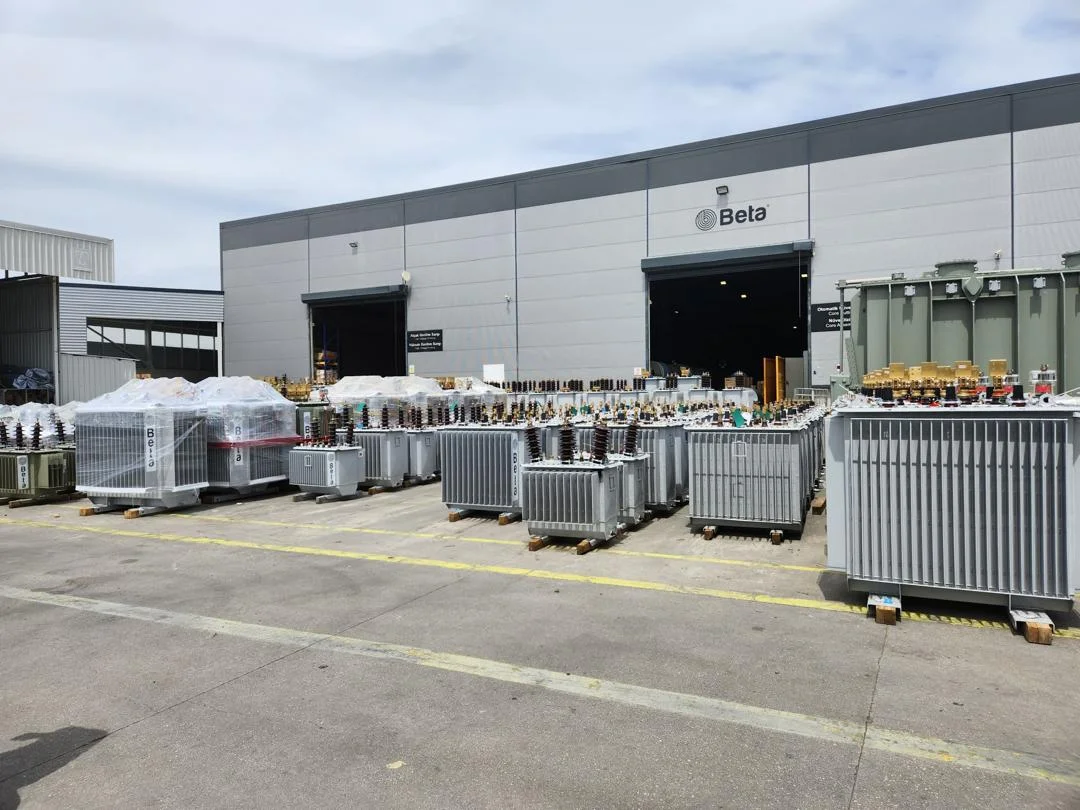 Rows of distribution transformers staged at manufacturing facility yard